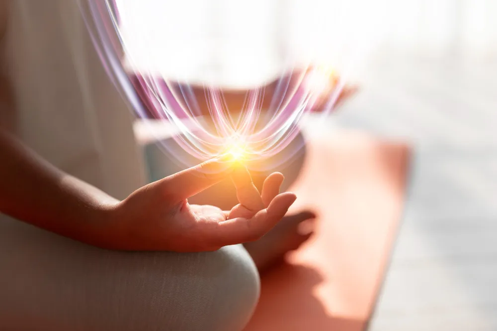 A meditating hand in mudra with flowing light trails.